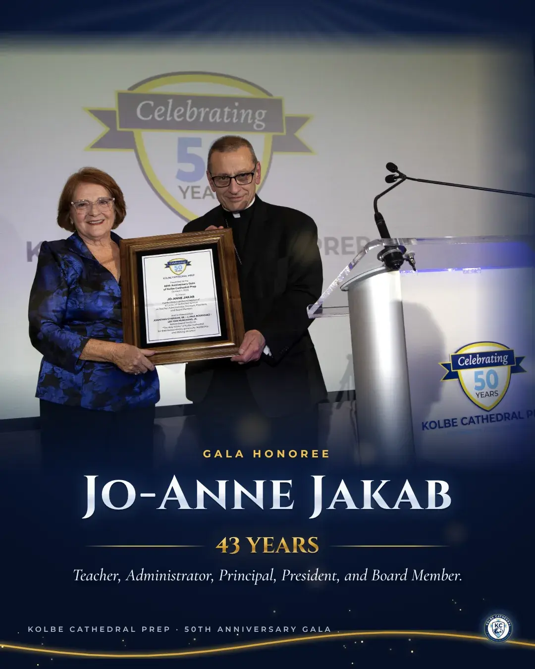 Jo-Anne Jakab and a member of the clergy holding her framed award on stage. Gala honoree Jo-Anne Jakab, 43 years: Teacher, Administrator, Principal, President, and Board Member.