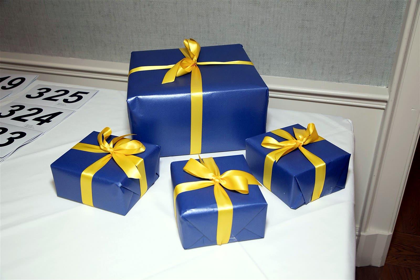 Blue gift boxes tied with yellow ribbon on a table beside printed bid-number cards.