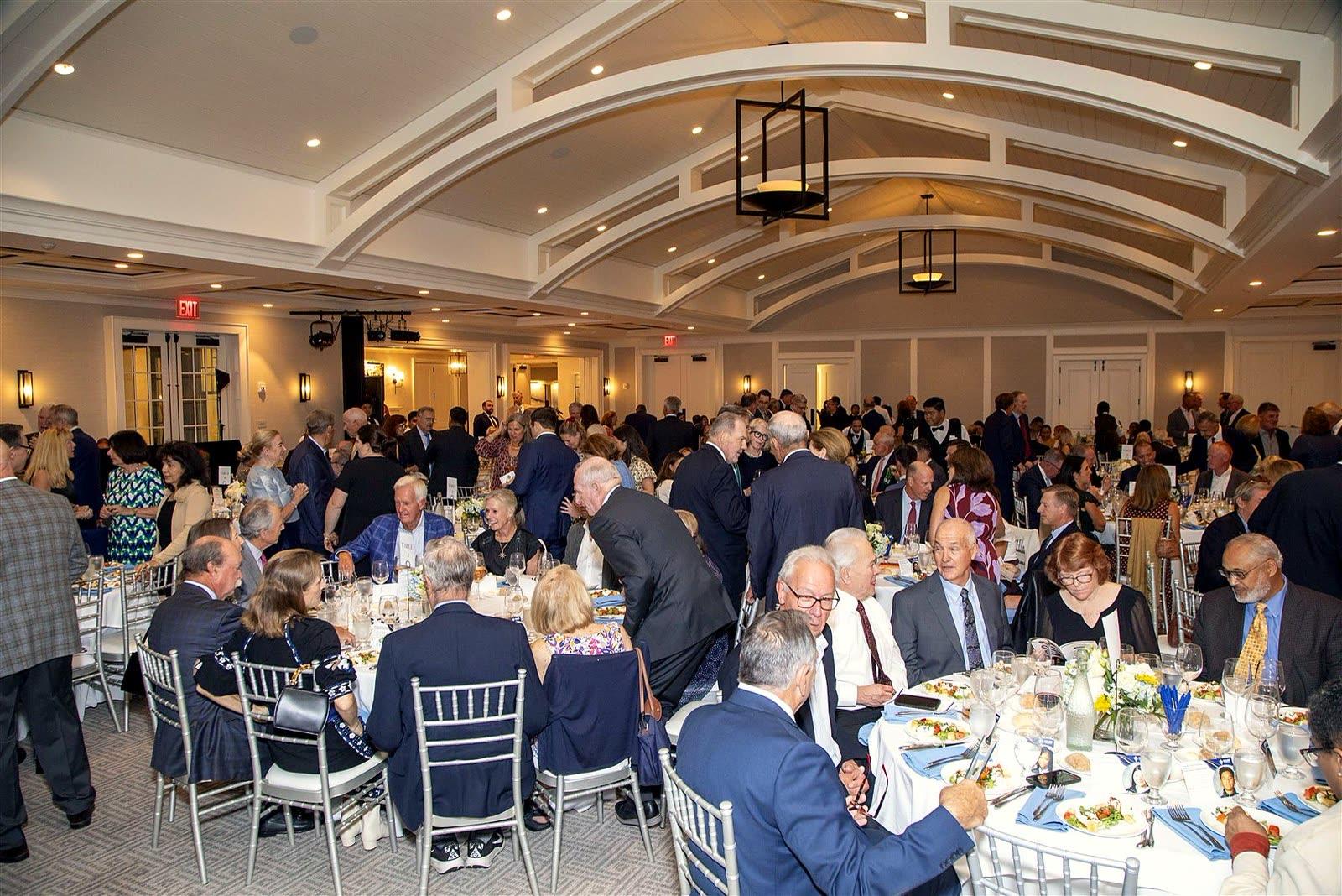 A full ballroom as guests settle in at their tables for dinner.