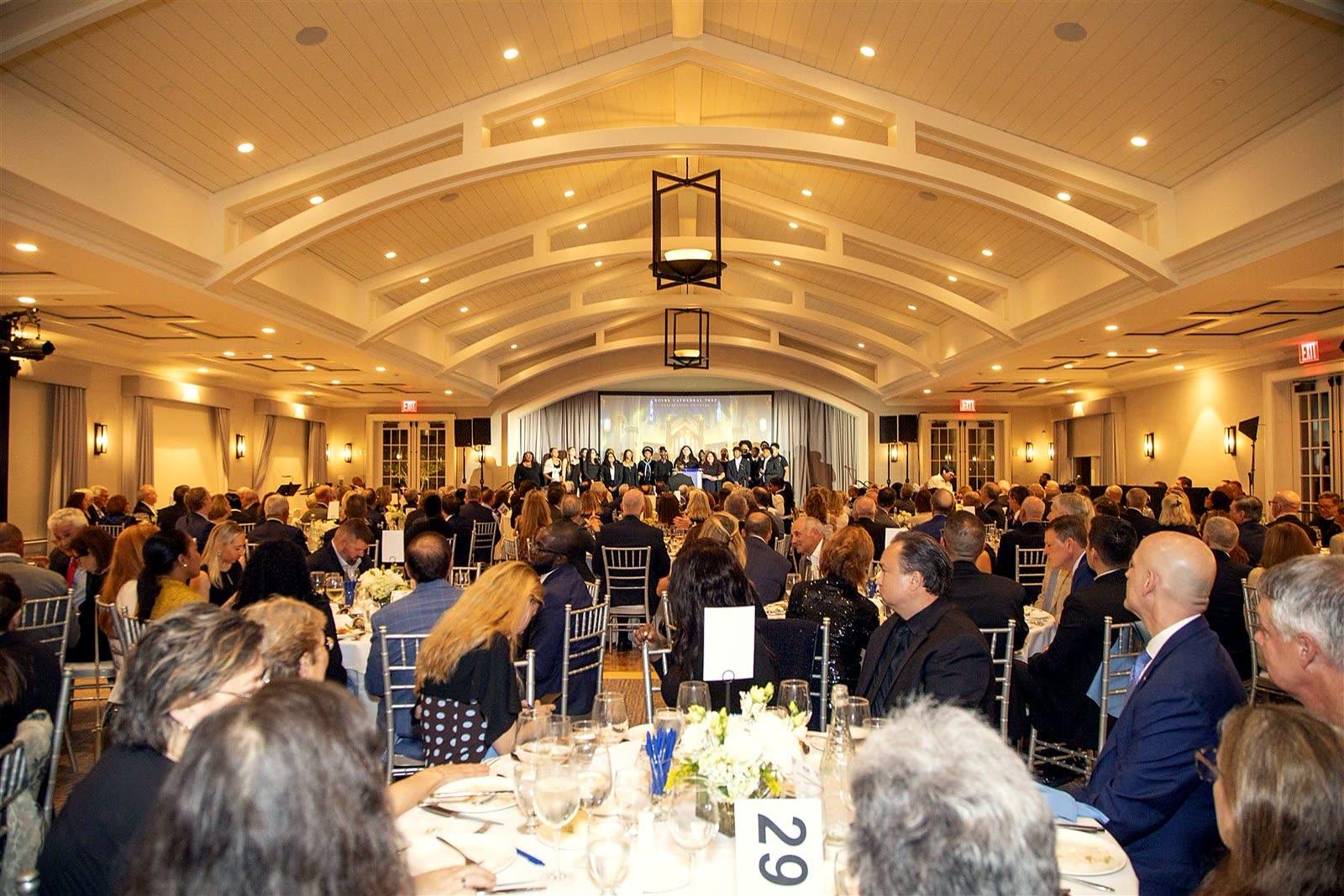 The whole ballroom, seen from the back, turned toward the student choir on stage.