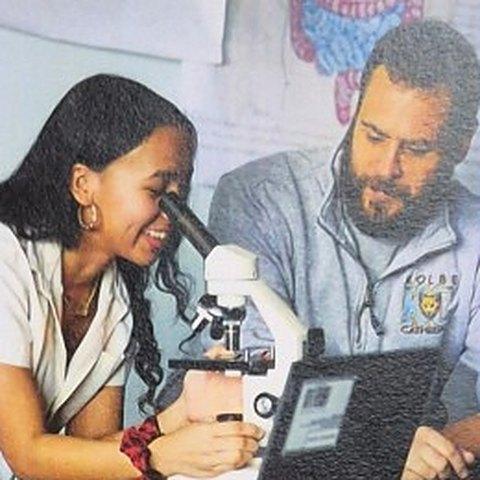 A Kolbe student looking through a microscope with a teacher